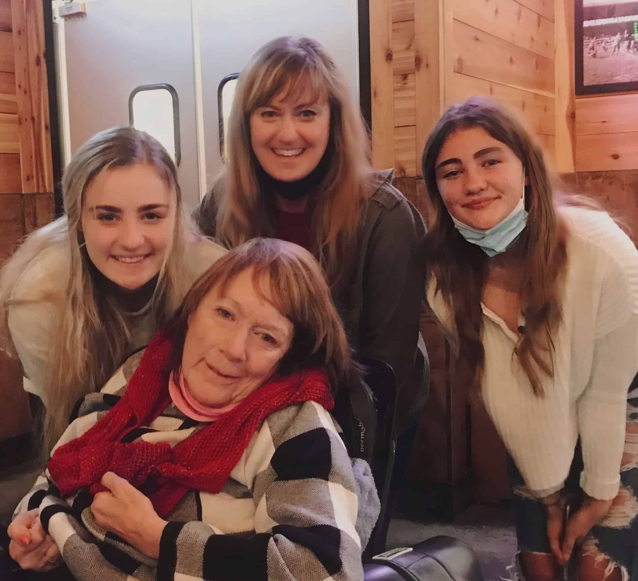 Group of four women smiling together indoors at Well Beings event.