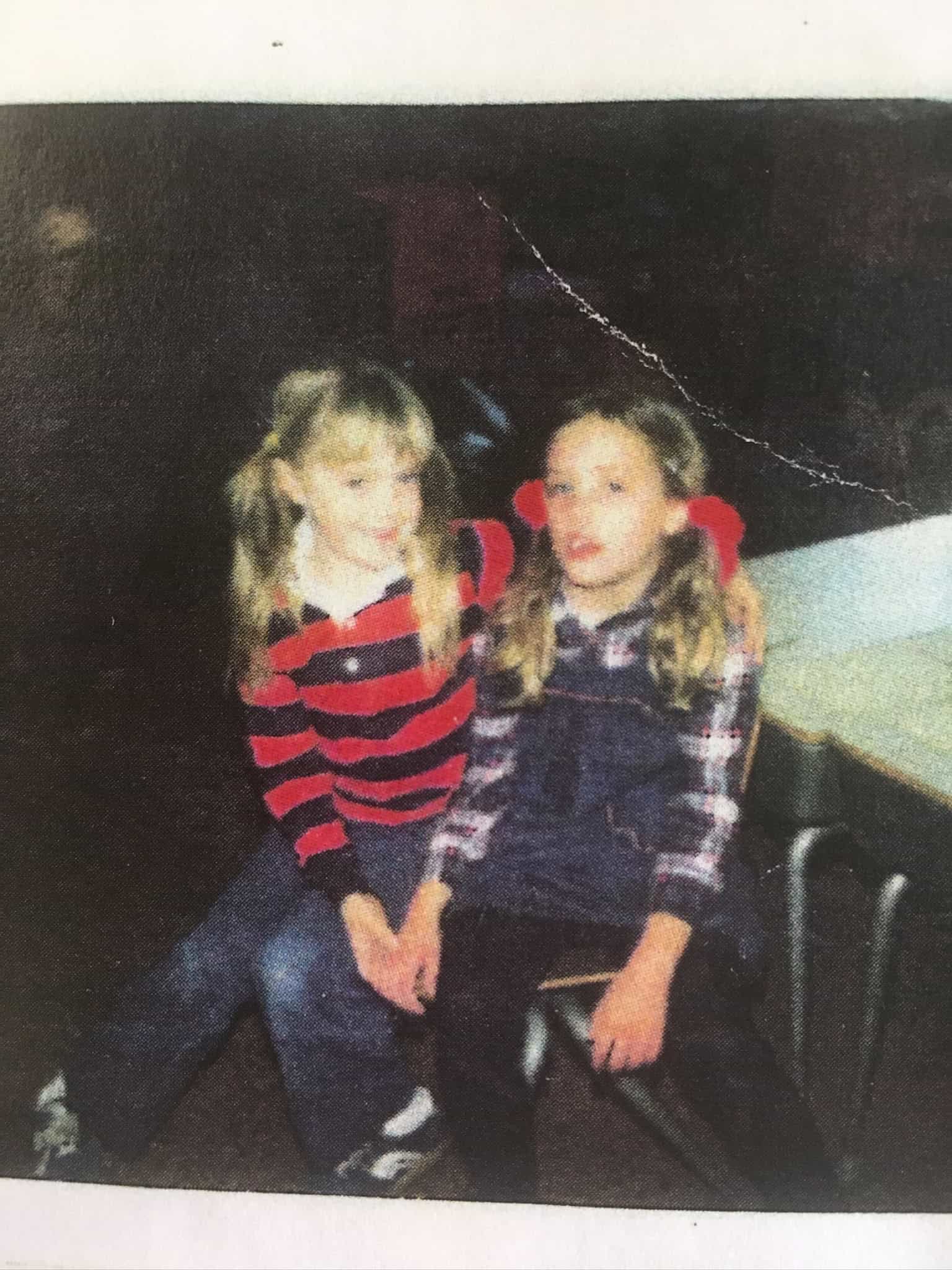 Two young girls sitting together in a classroom or similar setting.
