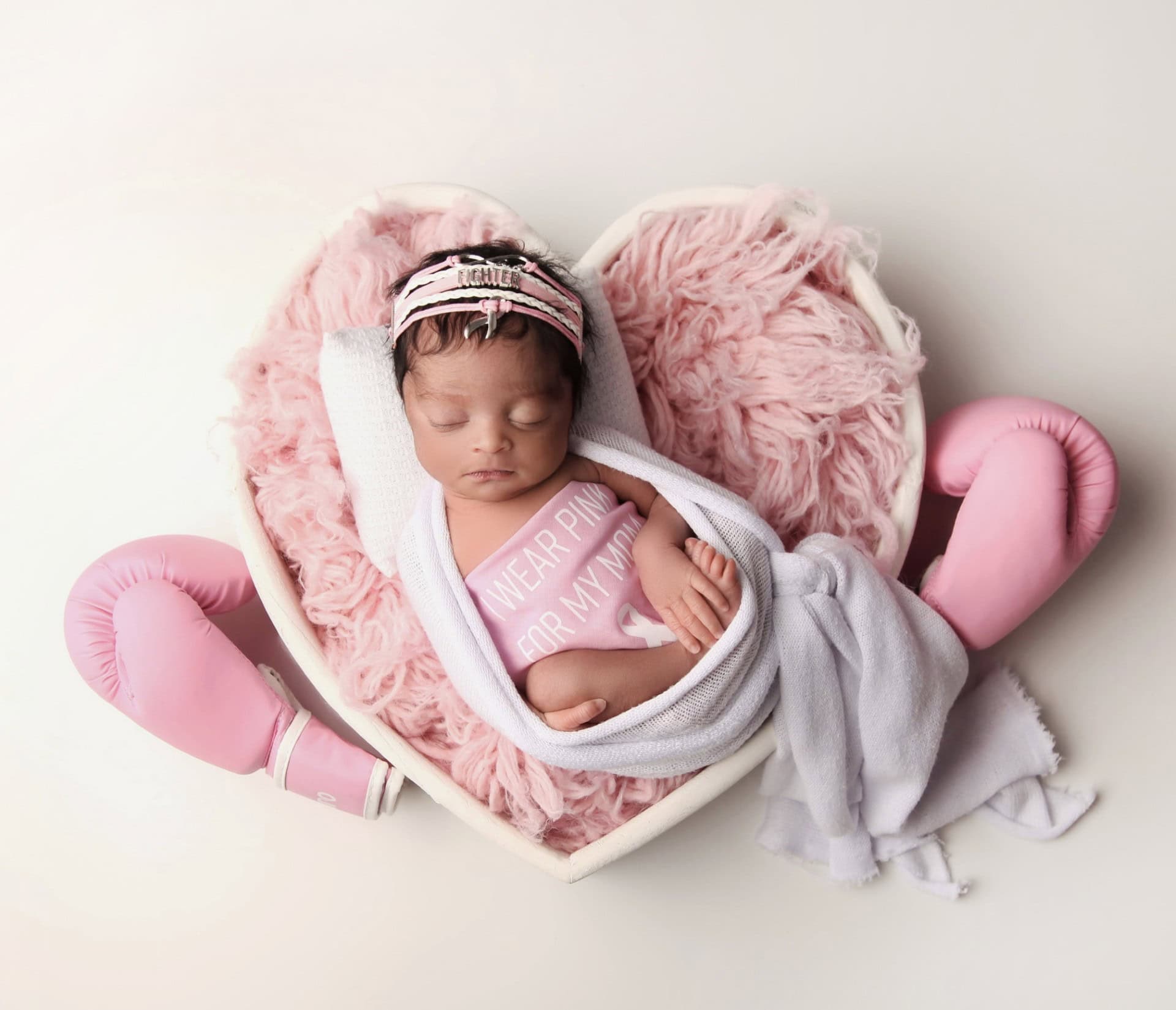 Alicia's newborn daughter Journi, wearing a pink ribbon onesie that reads I Wear Pink For My Mom